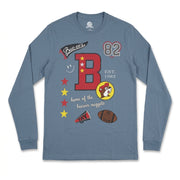 Slate blue long-sleeve t-shirt laid flat featuring a front collage graphic with a large red varsity letter B, Buc-ee's logo, football, megaphone, and "EST. 1982".