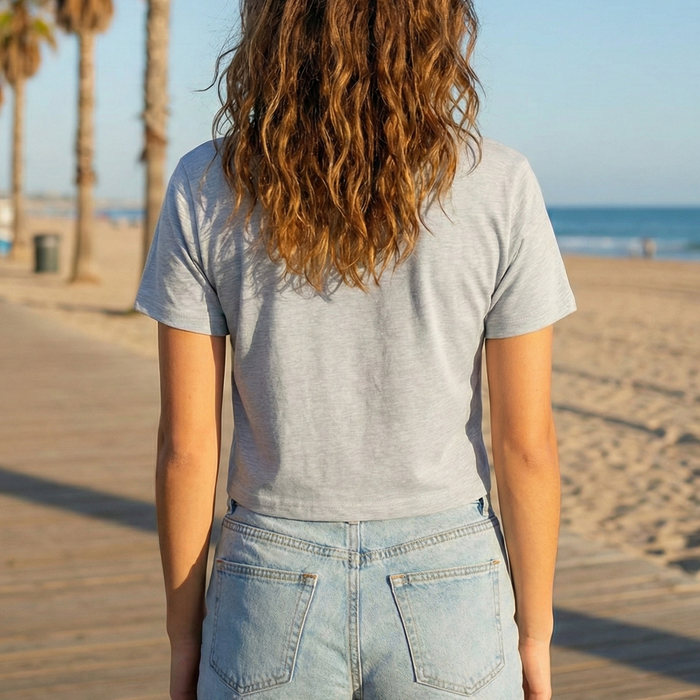 Person standing on a wooden boardwalk by the beach with palm trees in the background