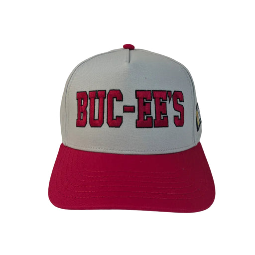 A product photo of a Buc-ee's Gray Hat with Red Embroidered Logo. A gray baseball cap with a vibrant red brim sitting on a white surface. The front of the cap features the text 'BUC-EE'S' embroidered in bold red letters. 