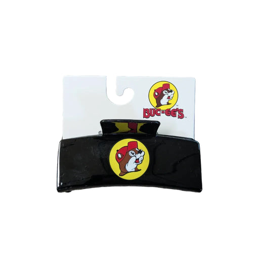 A sleek, rectangular black hair claw clip displayed on a white branded backing card. The center of the clip features a prominent yellow circular Buc-ee's logo with the iconic beaver mascot. The backing card also displays the full Buc-ee's logo and brand name in red at the top right.