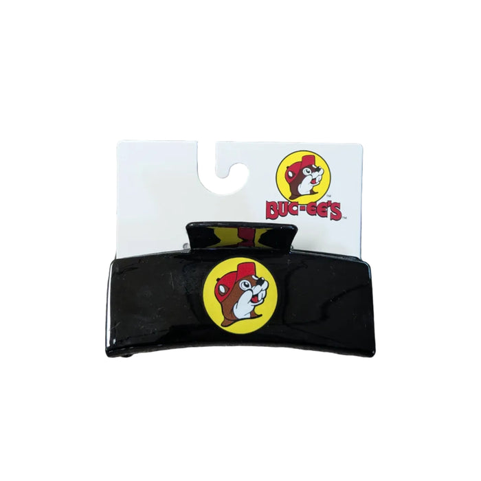 A sleek, rectangular black hair claw clip displayed on a white branded backing card. The center of the clip features a prominent yellow circular Buc-ee's logo with the iconic beaver mascot. The backing card also displays the full Buc-ee's logo and brand name in red at the top right.