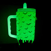 A green glow-in-the-dark plastic paint roller with a handle, decorated with black bat silhouettes, shown against a pitch-black background.