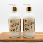 A photo of two frosted glass bottles of Buc-ee's Hand & Body Lotion on a light wooden cutting board against a white background. One bottle is labeled "Beaver Nuggets" and the other "Glazed Pecans." Both have white pumps and gold collars.