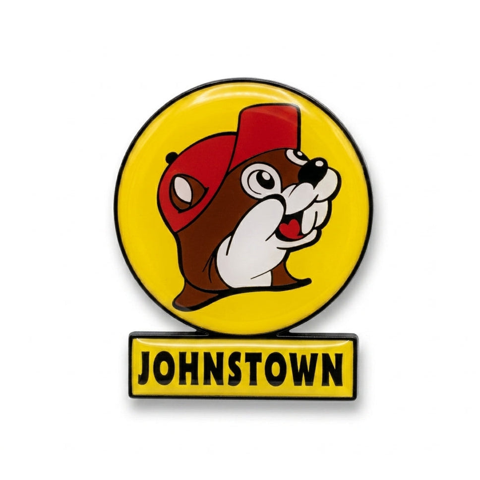 A circular yellow souvenir fridge magnet shaped like a Buc-ee's highway billboard sign on a solid white background. It features the smiling beaver mascot logo in a red cap inside a yellow circle, mounted over a rectangular yellow bar that reads "Johnstown" in bold black lettering.