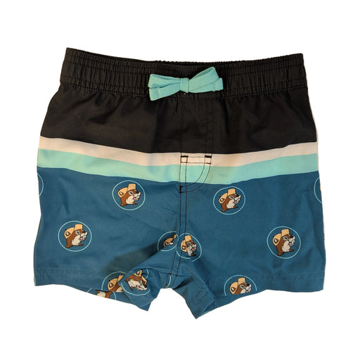 Infant-sized Buc-ee's Logo Colorblock swim shorts with a black and teal colorblock design and beaver logo pattern. The waistband features a small, fixed mint green decorative bow. Displayed on a clean white background.