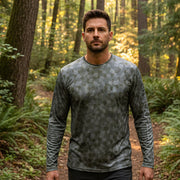 Buc-ee’s Long Sleeve Performance AOP Camo Shirt on a man in the forest.