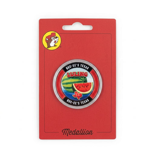 A circular metal souvenir medallion coin displayed inside a clear acrylic protective capsule on a red card. The coin face features a whole and sliced watermelon, a red Texas outline, "LULING" written across the top in red, and a black rim stamped with "BUC-EE'S TEXAS".