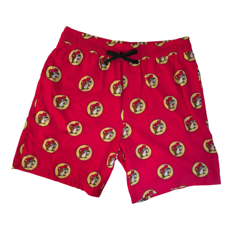 A flat lay view of bright red swim shorts featuring an all-over repeat pattern of the circular yellow and red Buc-ee’s beaver logo. The shorts include a black drawstring at the elastic waistband and are laid flat against a neutral background to show the design and fit.
