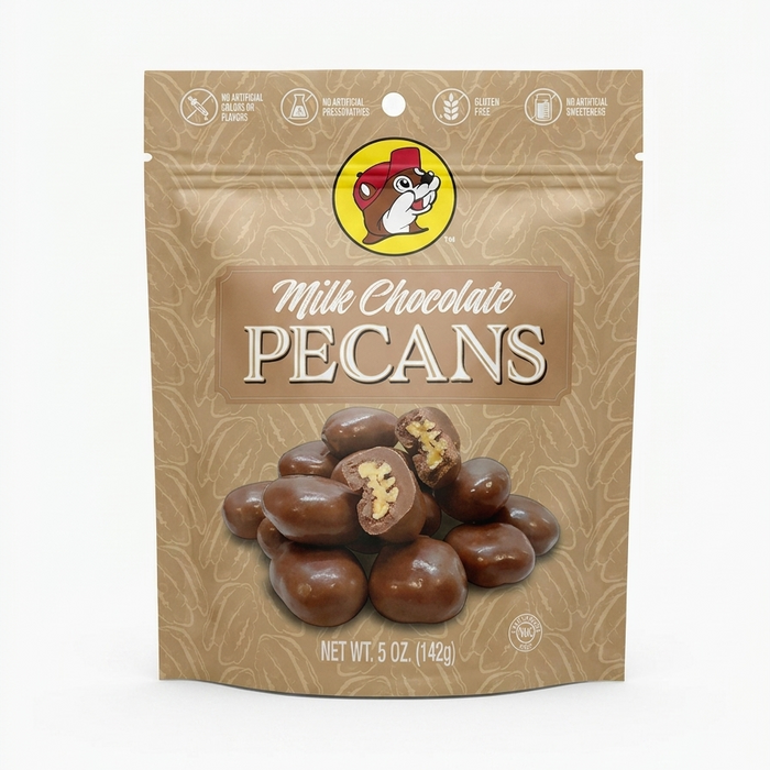 A professional product listing photo of a bag of Buc-ee's Milk Chocolate Pecans on a clean white background. The beige stand-up pouch features the iconic Buc-ee's beaver logo at the top center. Text below reads 'Milk Chocolate PECANS' above a pile of chocolate-covered pecans, two of which are cut in half. Dietary claims are at the top, and 'NET WT. 5 OZ. (142g)' is at the bottom. The lighting is bright and even.