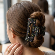 Close-up shot of a woman with her hair held up in a bun using a black Buc-ee's Halloween Neon Bat claw clip.