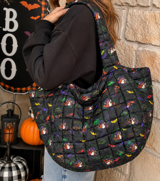 Buc-ee's Neon Bat Puffy Tote Bag on the shoulder of a woman with pumpkins  in the background.