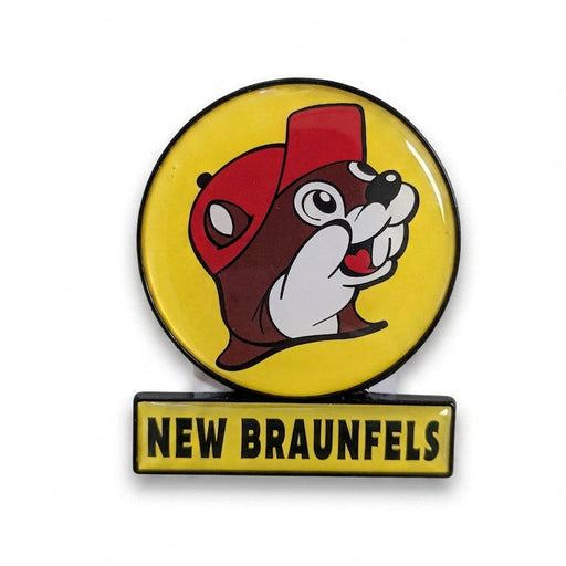 A circular yellow enamel magnet featuring the smiling Buc-ee's beaver wearing a red hat, with a small rectangular yellow sign attached directly below reading "NEW BRAUNFELS" in black text.