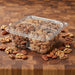 A clear plastic container filled with candied nuts, assorted and separated by section.