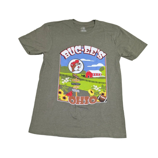 A heather military green t-shirt laid flat on a white surface. The central graphic features a large rectangular illustration with "BUC-EE'S" at the top and "OHIO" at the bottom. Inside the frame is a red barn, a Buc-ee's beaver logo, a red cardinal, sunflowers, a football, and a wooden signpost pointing toward "Wall of Jerky," "Beaver Nuggets," and "Clean Restrooms."