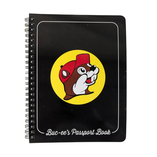A front view of the Buc-ee's Passport Book. It is a black spiral-bound notebook featuring the red-hatted beaver mascot in a yellow circle with the words "Buc-ee's Passport Book" in white script at the bottom. Displayed on a clean white background.