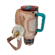 A photo of a tumbler inside a Buc-ee's pink crossbody tumbler bag carrier showing attached Buc-ee the Beaver round silicone straw topper charm in packaging.