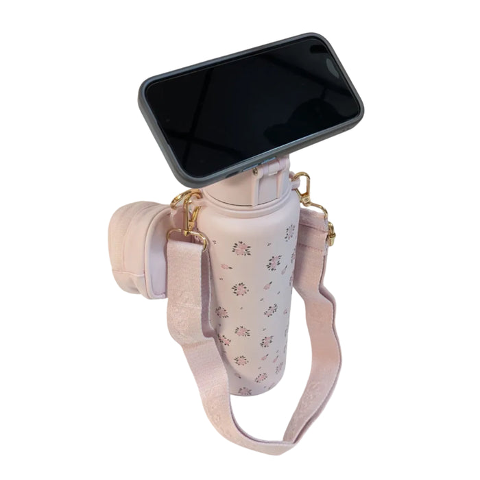 A smartphone in a black case shown balancing horizontally on top of the pink Buc-ee's Pink Floral Hands Free tumbler lid, demonstrating how the flip-up magnetic ring acts as a hands-free phone stand. Displayed on a white background.