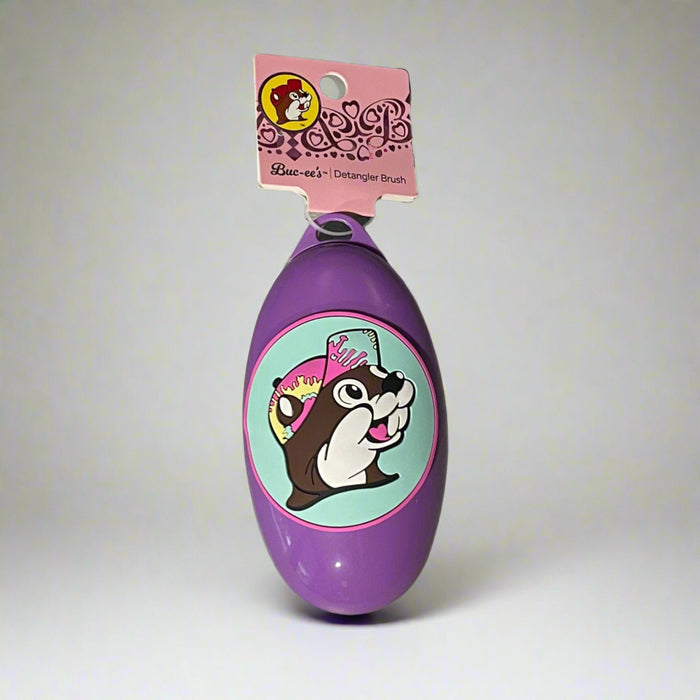 Buc-ee’s detangler brushes in two colors: one black with Buc-ee in a red cap, and one purple with Buc-ee surrounded by pink hearts, shown from front and back views.

