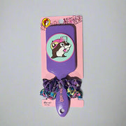 Two Buc-ee’s hair brush and scrunchie sets on display: one with a purple brush and heart scrunchies, the other with a black brush and colorful red-cap Buc-ee's theme scrunchies.


