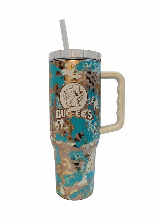 Buc-ee’s Ranch Leopard 40oz tumbler with a turquoise, tan, and metallic leopard print design, featuring the Buc-ee’s logo, a cream-colored handle, clear lid, and reusable straw, displayed on a white background.