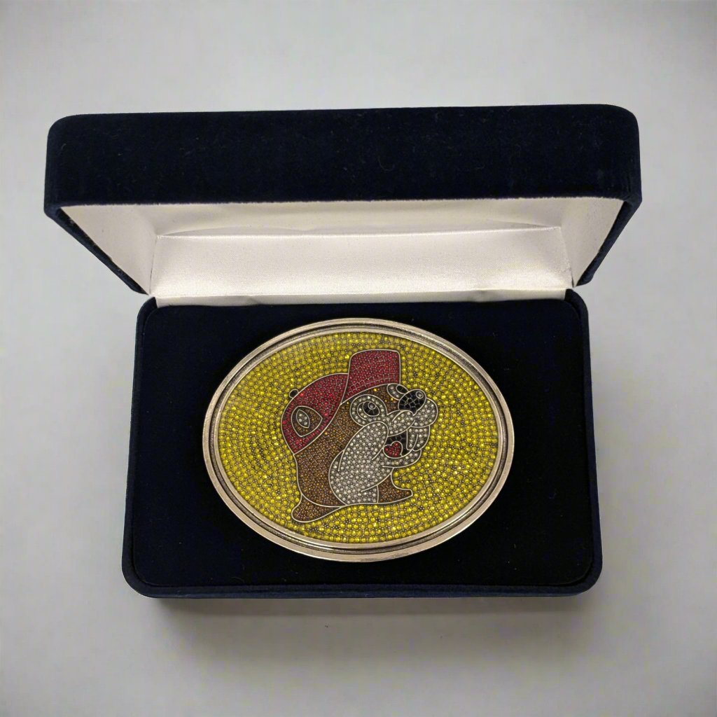 "Limited Edition Buc-ee's Rhinestone Belt Buckle in a black velvet display box, featuring the iconic beaver logo with sparkling rhinestones on a yellow background and red cap detail."






