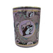 A close-up shot of a Buc-ee’s Blossoms & Bows scented candle in a purple glass jar with a gold lid. The decorative design features a repeating motif of pink bows and green leaves. The central logo shows Buc-ee the Beaver in a pink hat on a light pink circular backdrop with a gold-leaf border. The candle wax is a soft mauve-purple color. Displayed on a clean white background.
