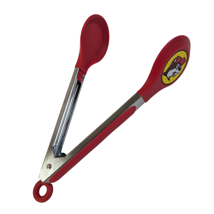 An open view of the Buc-ee's serving tongs, revealing the smooth red silicone spoon-shaped tips and the iconic round beaver cartoon mascot logo on one side.