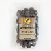 A professional product listing photo of a clear, resealable bag of Buc-ee's Small Batch Milk Chocolate Pecans on a seamless white background. The transparent bag is filled with chocolate-covered pecans and features a tan, vintage-style label with the red-hatted beaver logo. The label text reads "SMALL BATCH MILK CHOCOLATE PECANS" with a net weight of "16 OZ. (454g)" at the bottom. The lighting is bright and crisp.