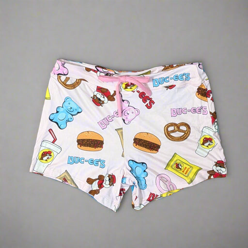 Close-up of Buc-ee’s pajama shorts showing playful snack icons like pretzels, jerky, and gummy bears on a pink background.