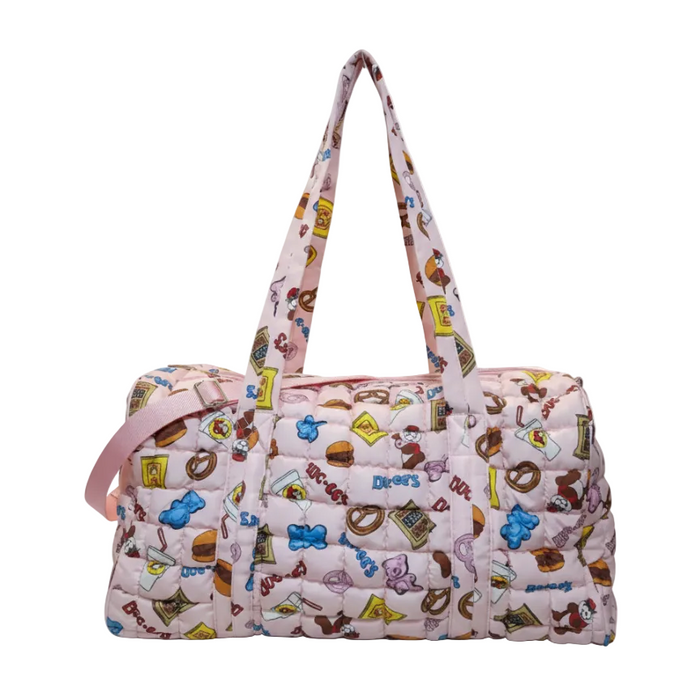 A clean product shot of the Buc-ee’s Snacks Pink Puffy Duffle Bag centered against a solid white background. The bag is made from light pink quilted fabric featuring a vibrant all-over print of Beaver Nuggets, pretzels, blue and pink gummy bears, and Buc-ee's soda cups. It features two long top carry handles held upright and a solid pink adjustable shoulder strap attached to the side. The front of the bag shows the continuous quilted snack pattern without any external pockets.