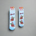 Two pairs of Buc-ee’s Snowflake Christmas Crew Socks, one kids’ size and one adult size, featuring a light blue background with snowflakes and Buc-ee riding in a Christmas sleigh filled with presents.