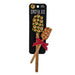 A retail package containing two Buc-ee's baking spatulas with natural wood handles, crossed over each other. A decorative red fabric ribbon with white polka dots is tied in a bow around the handle of the smaller spatula. The large spatula has a black silicone head and the smaller one has a red head, both covered in a repeating yellow Buc-ee's beaver logo print.