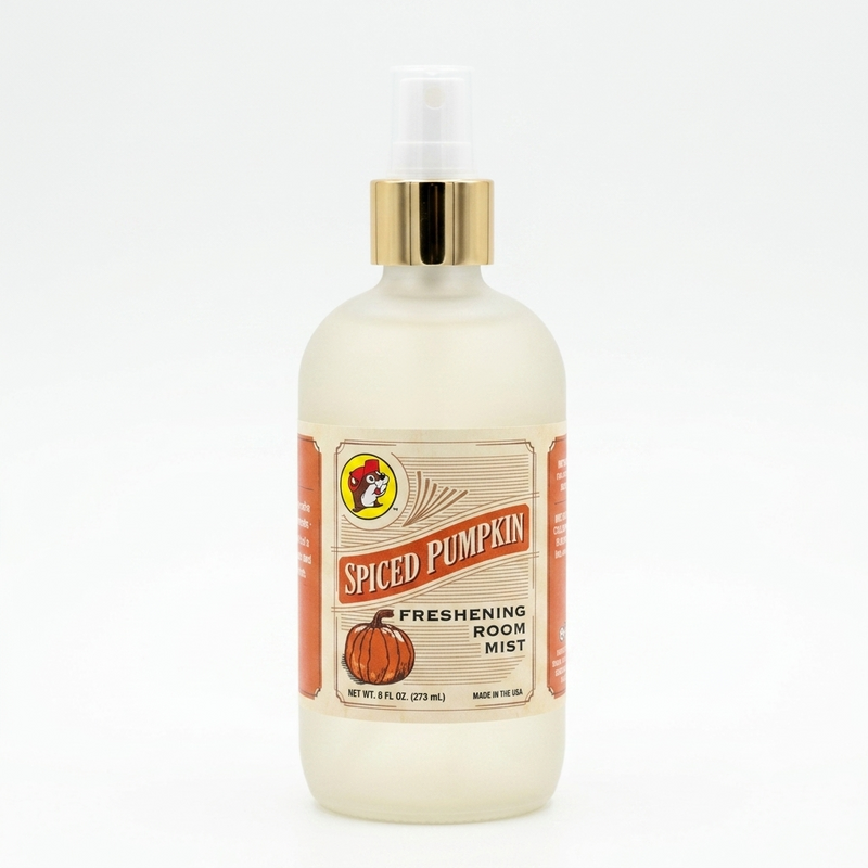A square, close-up photograph of a frosted glass bottle with a clear spray nozzle and a gold cap, containing a light yellow-colored liquid room mist. A vintage-style paper label wrap around the front features a cartoon drawing of a beaver in a hat and the words "SPICED PUMPKIN," "FRESHENING ROOM MIST," "NET WT. 8 FL OZ (273 ML)," and "MADE IN THE USA," along with a stylized drawing of a pumpkin. The background is solid white.