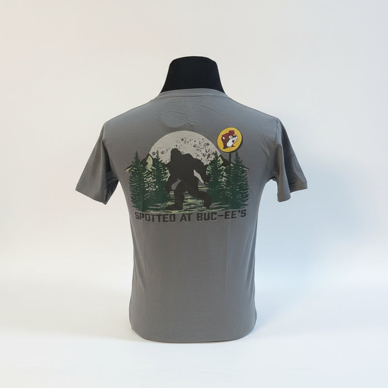 The Buc-ee’s “Spotted at Buc-ee’s” Shirt captures the legendary moment Bigfoot was seen grabbing snacks under the Texas stars. Featuring a classic gray tee with a bold Buc-ee’s logo on the front and a mysterious Bigfoot silhouette against a moonlit forest on the back, this shirt is perfect for fans of roadside adventures and tall tales alike.