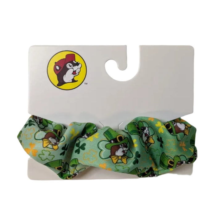 A Buc-ee's scrunchie featuring a green-to-white ombre gradient with a pattern of Buc-ee in a leprechaun hat, displayed on a clean white background.