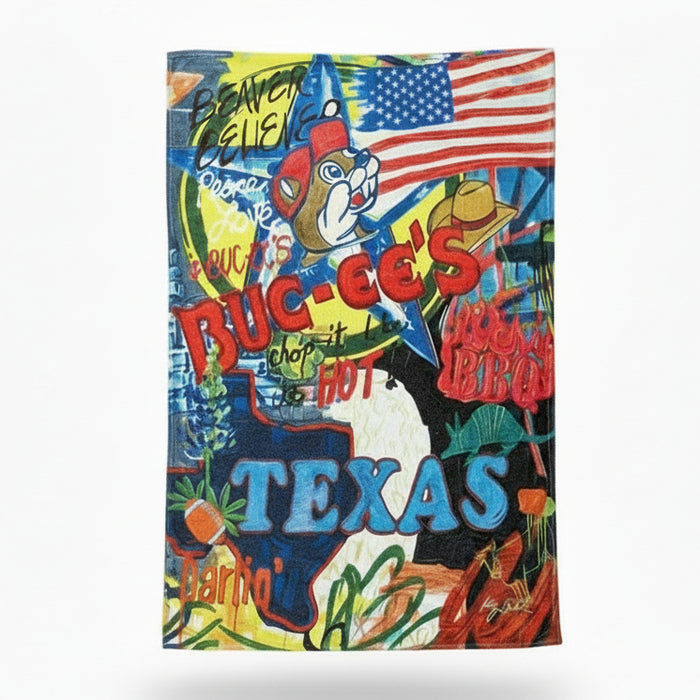 Buc-ee’s Texas plush blanket with colorful collage design, American flag, Buc-ee the Beaver graphic, and large “TEXAS” lettering laid flat and displayed on a clean white background.