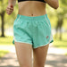 A woman running wearing the Buc-ee's Turquoise Track Shorts featuring mesh side panels, and a small Buc-ee's beaver logo on the leg.