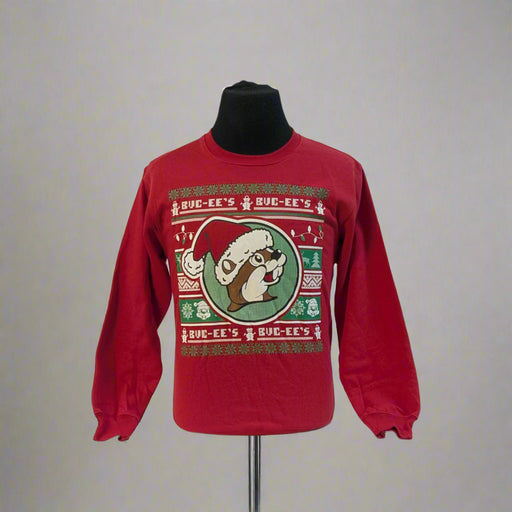 Buc-ee’s Ugly Christmas Sweater 2025 in red with Buc-ee wearing a Santa hat, surrounded by festive snowflake and reindeer sweater patterns.