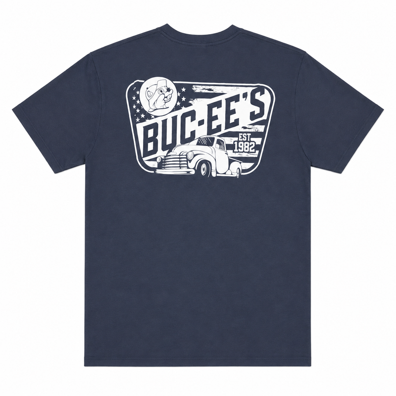 Back view of a navy blue Buc-ee’s T-shirt featuring a large distressed white vintage graphic with bold “BUC-EE’S” lettering, “EST. 1982,” a beaver emblem, stars, and a classic pickup truck, displayed on a clean white background.