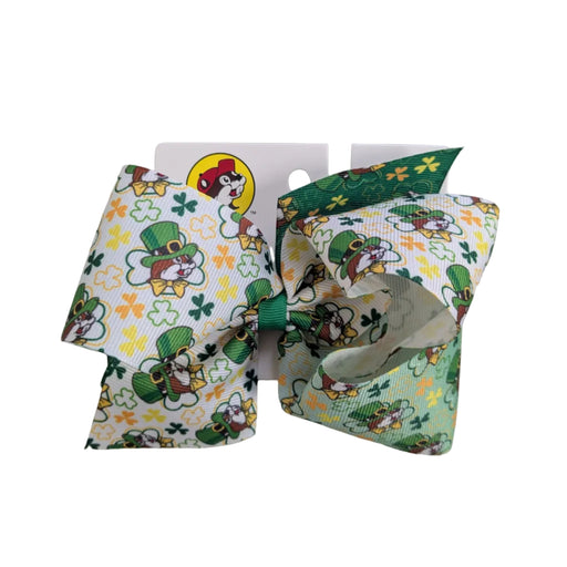A Buc-ee's St. Patrick's Day hair bow with a vibrant white to green ombre base covered in a pattern of Buc-ee the beaver wearing a leprechaun hat, lucky shamrocks, and gold accents, displayed on a clean white background.