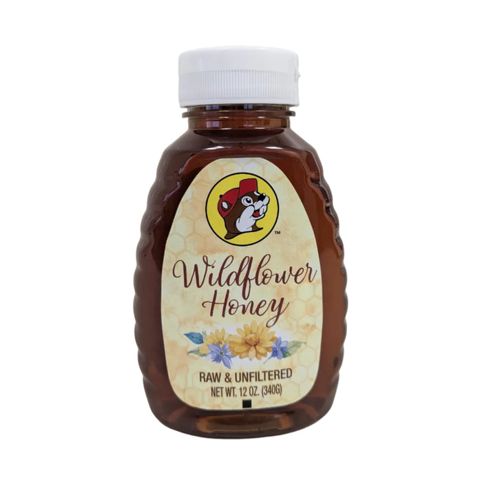 A 12 oz. plastic squeeze bottle of Buc-ee's Wildflower Honey standing upright against a white background. The container is a clear, amber-tinted bottle with distinct ribbed edges on the sides and a white plastic cap. The cream-colored label features a subtle honeycomb pattern, the round Buc-ee's beaver logo, cursive text reading "Wildflower Honey", an illustration of yellow and purple wildflowers, and the text "RAW & UNFILTERED" and "NET WT. 12 OZ. (340g)".