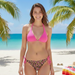 A woman on a beach wearing a Buc-ee's Leopard Bikini Set. A bright pink triangle bikini top and leopard print with pink Buc-ee beaver logos bottoms, with pink side ties.