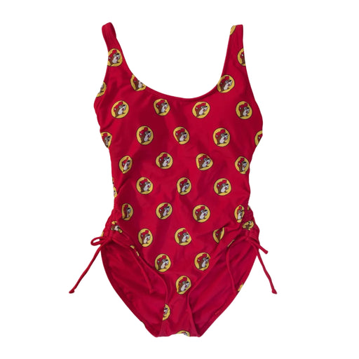 A Buc-ee's Red Logo women’s one-piece swimsuit featuring a scoop neckline and adjustable side-tie drawstrings at the hips to customize the leg height and fit. A vibrant, repeating pattern of the yellow and red Buc-ee’s beaver logo over the red swimsuit base. 