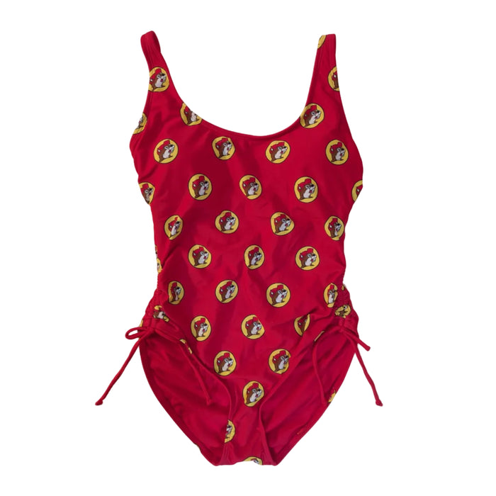 A Buc-ee's Red Logo women’s one-piece swimsuit featuring a scoop neckline and adjustable side-tie drawstrings at the hips to customize the leg height and fit. A vibrant, repeating pattern of the yellow and red Buc-ee’s beaver logo over the red swimsuit base. 