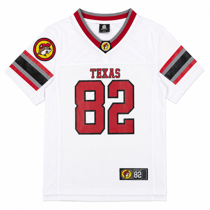 Front view of a white youth football jersey featuring red and grey "TEXAS 82" text on breathable mesh, sleeve stripes, and a Buc-ee's jock tag near the hem.