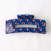 Blue hair clip with red and white pattern on a white background