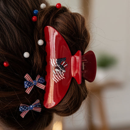 Red hair clip with a white card featuring a logo on a cardboard background