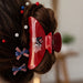 Red hair clip with a white card featuring a logo on a cardboard background