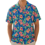 Man wearing a colorful floral shirt on a beach with palm trees.