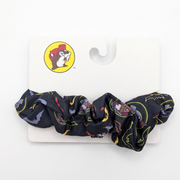 A black fabric scrunchie with a colorful cartoon character print, attached to a white display card featuring the yellow and red logo of the brand Soukai.